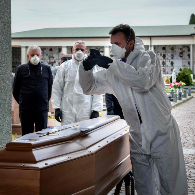 TOPSHOT - This picture taken on March 23, 2020 shows a pallbearer taking a picture of a coffin for the relatives of a deceased person at the cemetery of Grassobbio in the province of Bergamo, as they could not attend the ceremony because they are in quarantine as a result of the COVID-19 novel coronavirus. (Photo by Piero CRUCIATTI/AFP)