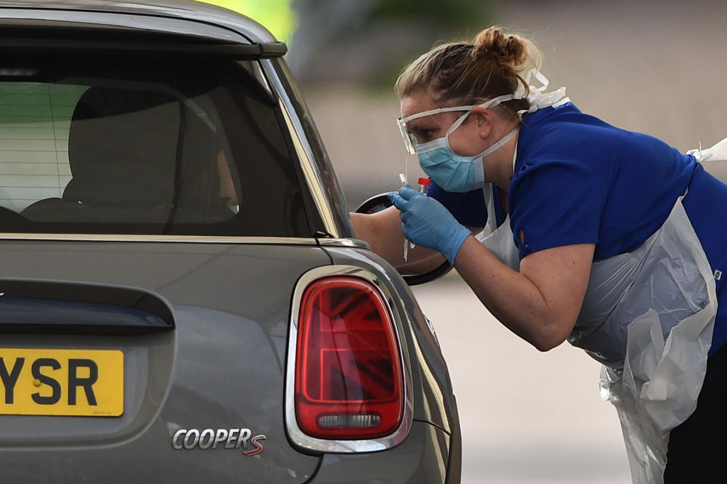 A medical staff member tests an NHS worker for the novel coronavirus COVID-19 at a drive-in facility set up in the carpark of Chessington World of Adventures in Chessington, Greater London on March 28, 2020. - Britain on March 24 said it will open a 4,000-bed field hospital at a London exhibition centre to treat coronavirus cases in the latest measure to tackle the outbreak after the government ordered a nationwide lockdown. (Photo by Glyn KIRK/AFP)