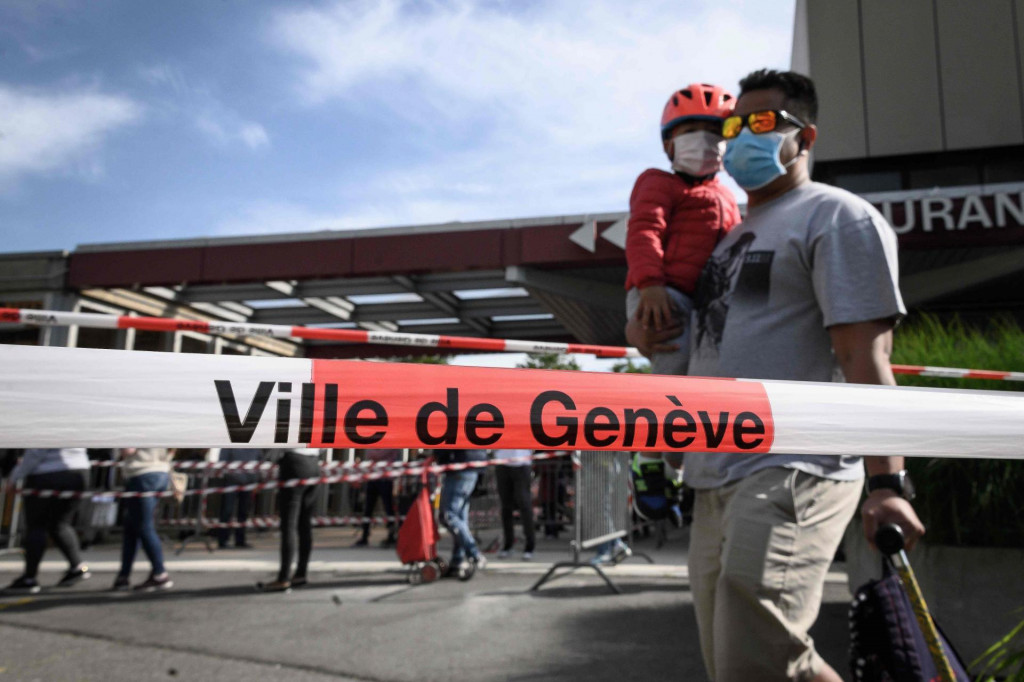 A father and his son wearing protective face masks queue behind warning police tape at a free food distribution on May 9, 2020 in Geneva as the COVID-19 pandemic casts a spotlight on the usually invisible poor people of Geneva, one of the world&amp;#39;s most expensive cities. (Photo by Fabrice COFFRINI/AFP)