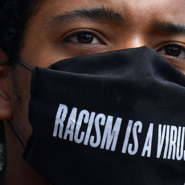 A protester wears a protective face covering with the slogan ”Racism is a Virus” written on the fabric as he listens to speeches at a gathering in support of the Black Lives Matter movement at Marble Arch in London on July 5, 2020, in the aftermath of the death of unarmed black man George Floyd in police custody in the US. (Photo by JUSTIN TALLIS/AFP)