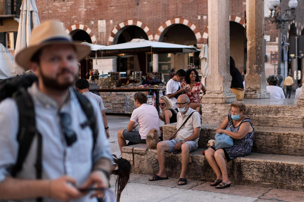 Tourists wearing protective face masks take a break in Piazza delle Erbe on July 25, 2020 in Verona, northern Italy. (Photo by MARCO BERTORELLO/AFP)