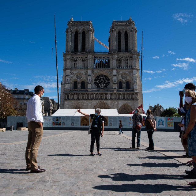 A guide gives explanations to tourists in front of Notre-Dame-de-Paris cathedral in Paris, on September 9, 2020. - Work on Notre-Dame&amp;#39;s reconstruction after last year&amp;#39;s fire has been plagued by delays due to bad weather, concerns over lead pollution, and most recently the coronavirus pandemic. It was only in early June that workers began the delicate task of removing tons of metal scaffolding that melted together in the fire -- renovation work was underway when the blaze struck. (Photo by Martin BUREAU/AFP)