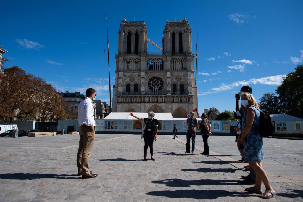 A guide gives explanations to tourists in front of Notre-Dame-de-Paris cathedral in Paris, on September 9, 2020. - Work on Notre-Dame&amp;#39;s reconstruction after last year&amp;#39;s fire has been plagued by delays due to bad weather, concerns over lead pollution, and most recently the coronavirus pandemic. It was only in early June that workers began the delicate task of removing tons of metal scaffolding that melted together in the fire -- renovation work was underway when the blaze struck. (Photo by Martin BUREAU/AFP)
