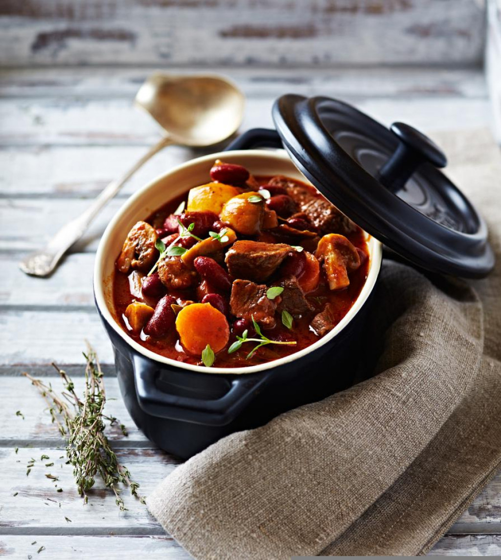 Beef goulash with mushrooms and vegetables. Symbolic image. Concept for a tasty and hearty dish. Bright wooden background