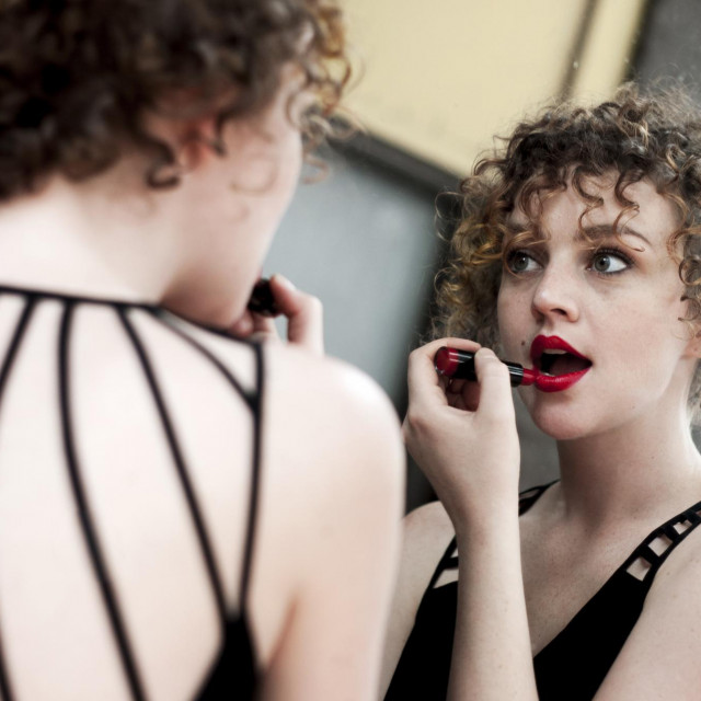 Portrait of young woman applying lipstick in mirror AFP