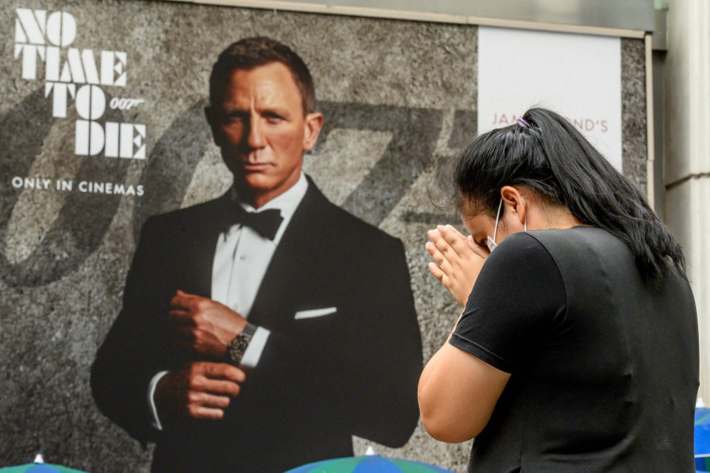 (Simbolična) molitva za kina ispred plakata Bond-filma &amp;#39;Za smrt nema vremena&amp;#39; pored hrama Erawan u Bangkoku