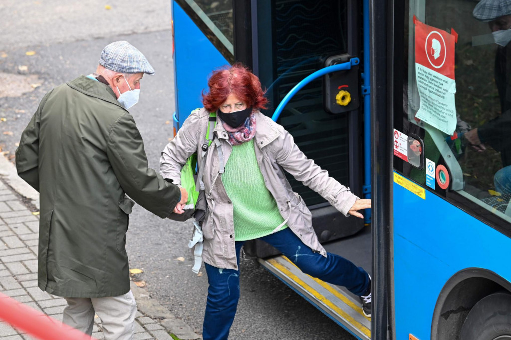 Wearing their facemasks, an elderly Hungarian couple get off the bus at the St Janos Hospital of Budapest, 12th district on October 18, 2020, amid the novel coronavirus COVID-19 pandemic. - The new coronavirus COVID-19 was detected by 1474 Hungarian citizens on October 17, 2020, thus increasing the number of infected people identified in Hungary to 46,290. (Photo by ATTILA KISBENEDEK/AFP)