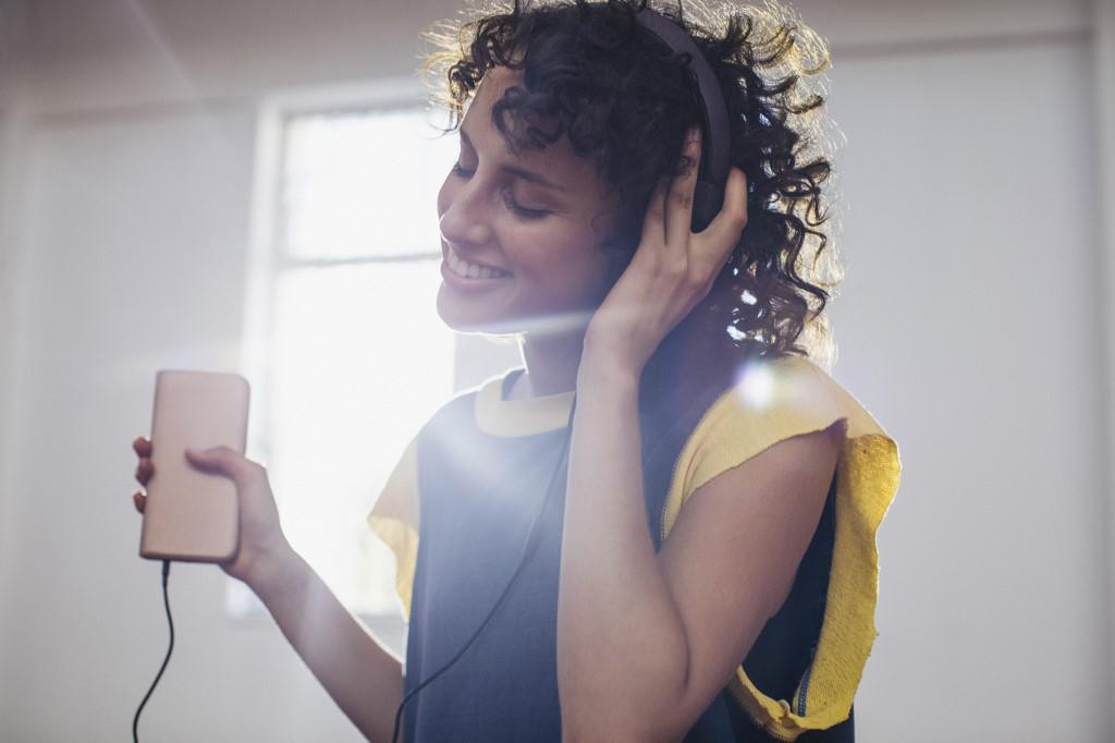 Smiling, carefree young woman listening to music with headphones and mp3 player.