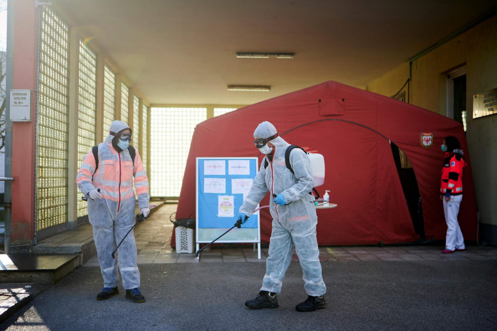 Workers wearing protective clothes disinfect one of the entrances at the Community Health Centre in Kranj, Slovenia, on March 23, 2020 amid concerns over the spread of the COVID-19 coronavirus. (Photo by Jure Makovec/AFP)