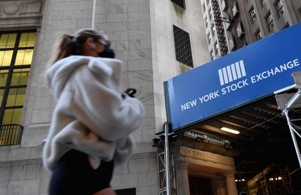 A woman walks past the New York Stock Exchange (NYSE) at Wall Street on November 16, 2020 in New York City. - Wall Street stocks rose early following upbeat news on a coronavirus vaccine and merger announcements in the banking and retail industries. (Photo by Angela Weiss/AFP)