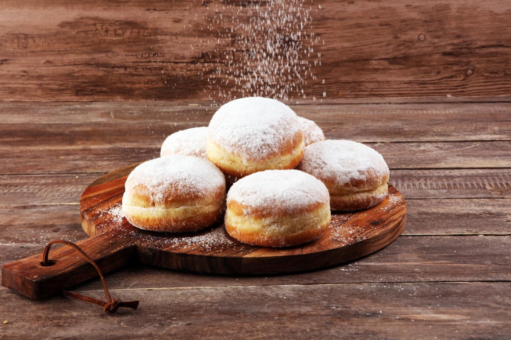 German donuts with jam and icing sugar. Carnival powdered sugar raised donuts.