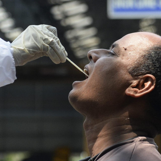 A health official takes a swab sample from a rail worker for a RT-PCR Covid-19 coronavirus test at a railway yard in Chennai on April 9, 2021 as India surged past 13 million coronavirus cases. (Photo by Arun SANKAR/AFP)