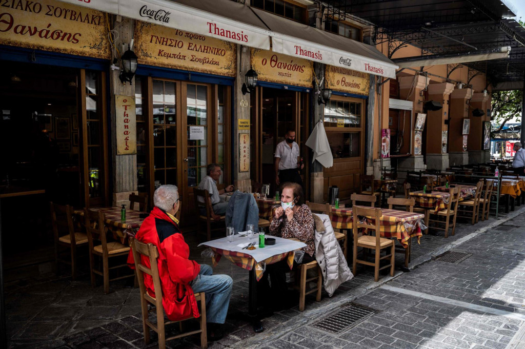 Ljudi sjede na terasi restorana na trgu Monastiraki u Ateni 3. svibnja 2021., dok se restorani i kafići u Grčkoj otvaraju nakon šest mjeseci zatvorenosti zbog pandemije Covid-19