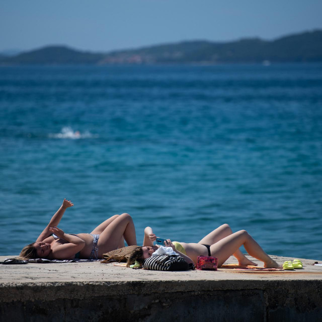 Temperatura mora u Zadru je oko 20 stupnjeva Celzijusa, a na plazi ispod hotela Kolovare Zadrani i turisti uzivaju u suncanju i kupanju.