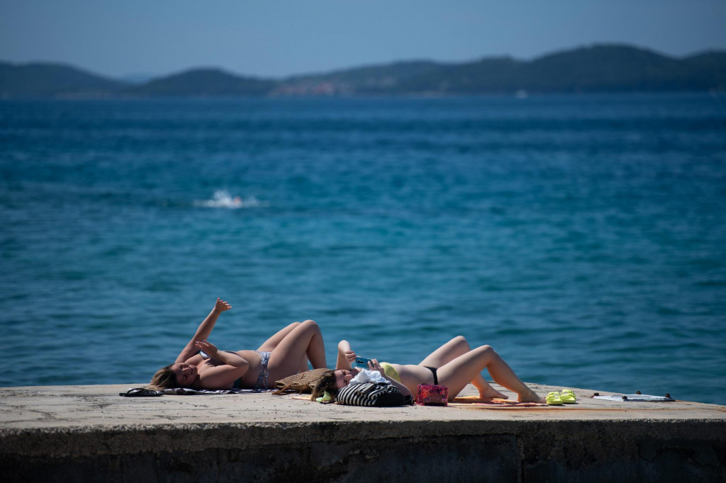 Temperatura mora u Zadru je oko 20 stupnjeva Celzijusa, a na plazi ispod hotela Kolovare Zadrani i turisti uzivaju u suncanju i kupanju.