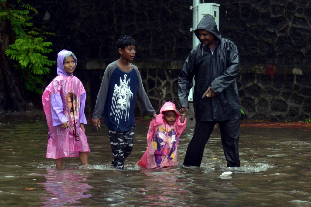 A family wades along a waterlogged street following a heavy monsoon rainfall in Mumbai on June 9, 2021. (Photo by Sujit Jaiswal/AFP)