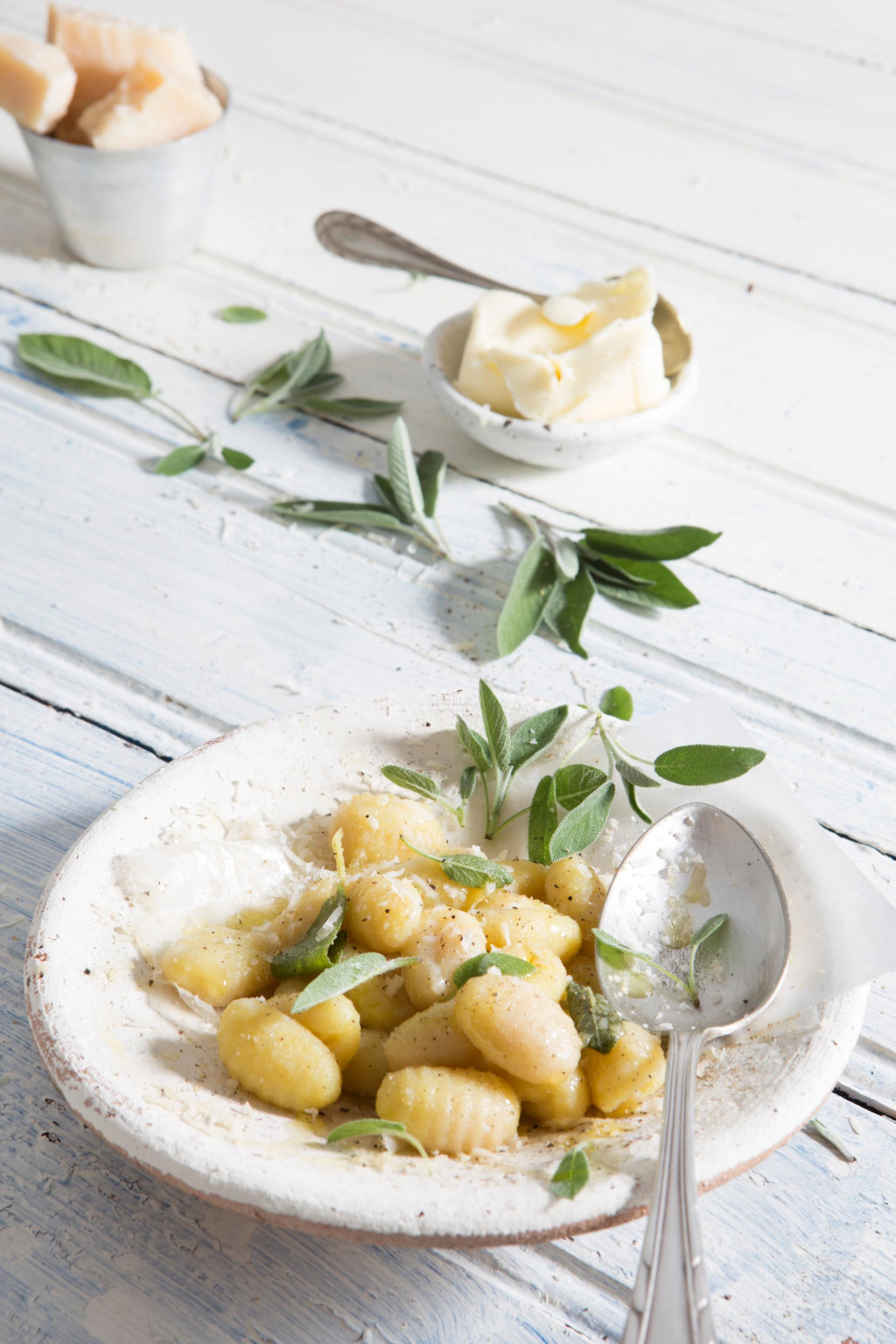 gnocchi with sage and butter on white plate on white wood