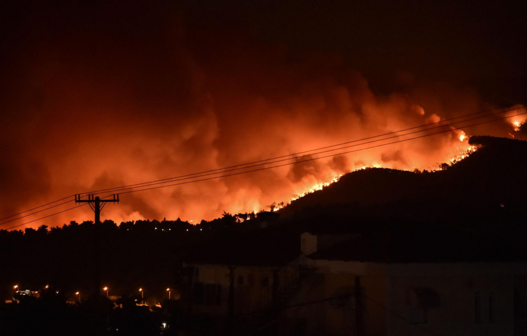 This picture taken on August 5, 2021 shows flames rising from a fire spreading around Kapandriti, on the outskirts of Athens. - Firefighters were battling a series of raging blazes in sweltering heat on August 5, 2021, in western and eastern Greece, and near Athens where a fire that had been coming under control regained strength. (Photo by Louisa GOULIAMAKI/AFP)