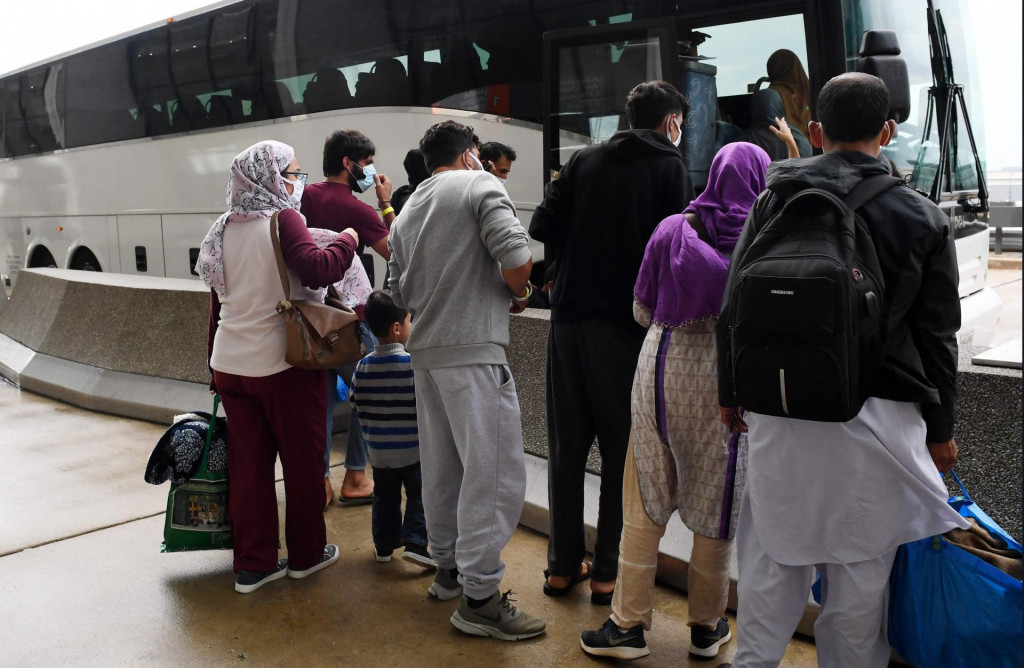 Afghan refugees board a bus after arriving at Dulles International Airport on August 27, 2021 in Dulles, Virginia, after being evacuated from Kabul following the Taliban takeover of Afghanistan. - The Pentagon said on Friday the ongoing evacuation from Afghanistan faces more threats of attack a day after a suicide bomber and possible associated gunmen killed scores at a Kabul airport gate. (Photo by Olivier DOULIERY/AFP)