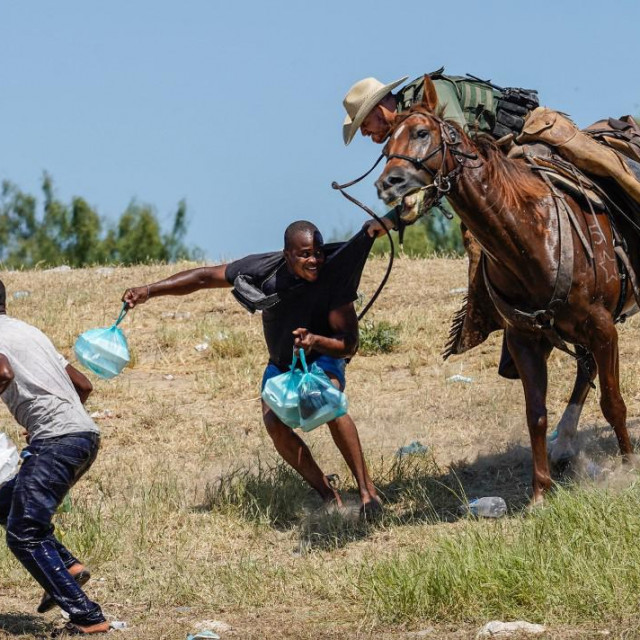Agent granične ophodnje Sjedinjenih Država na konju pokušava spriječiti migranta iz Haitija da uđe u kamp na obali Rio Grande 