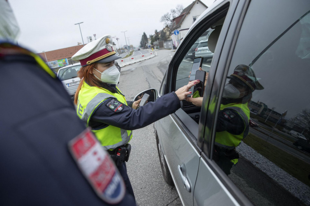 Austrijski policajac provjerava vozaćevu potvrdu o cijepljenju na pametnom telefonu tijekom kontrole prometa u Grazu, Austrija
