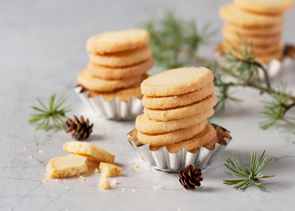 Homemade sugar cookies in vintage baking tins with christmas tree twigs.
