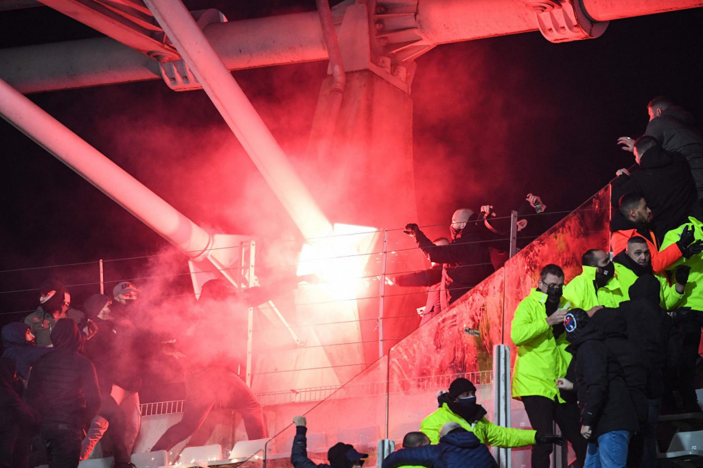 Supporters hold a flare during the French Cup round of 64 football match between Paris FC and Olympique Lyonnais (OL) at the Charlety stadium in Paris, on December 17, 2021. - The match was interrupted due to incidents in the stands. At half-time, several flares were launched toward Lyon supporters, and two improvised explosive devices also exploded. Spectators from this stand then descended on the lawn to move away from the scene of the incidents, preventing the resumption of the match. (Photo by Bertrand GUAY/AFP)