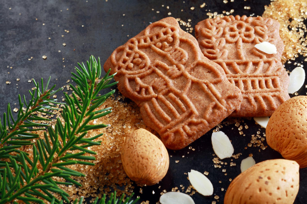 Spicy crunchy speculoos Christmas biscuits, a Dutch speciality confectionery originally baked for the feast of St Nicholas and decorated with religious patterns and pictures with almonds and fir twig