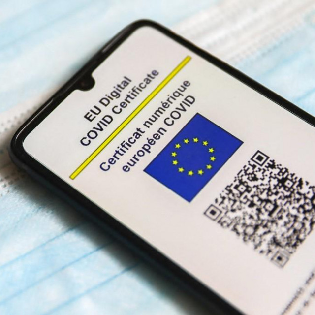 EU Digital COVID Certificate is displayed on a mobile phone screen photographed on surgical masks background for illustration photo during the spread of the fifth wave of the coronavirus pandemic. Gliwice, Poland on January 23, 2022. (Photo by Beata Zawrzel/NurPhoto) (Photo by Beata Zawrzel/NurPhoto/NurPhoto via AFP)