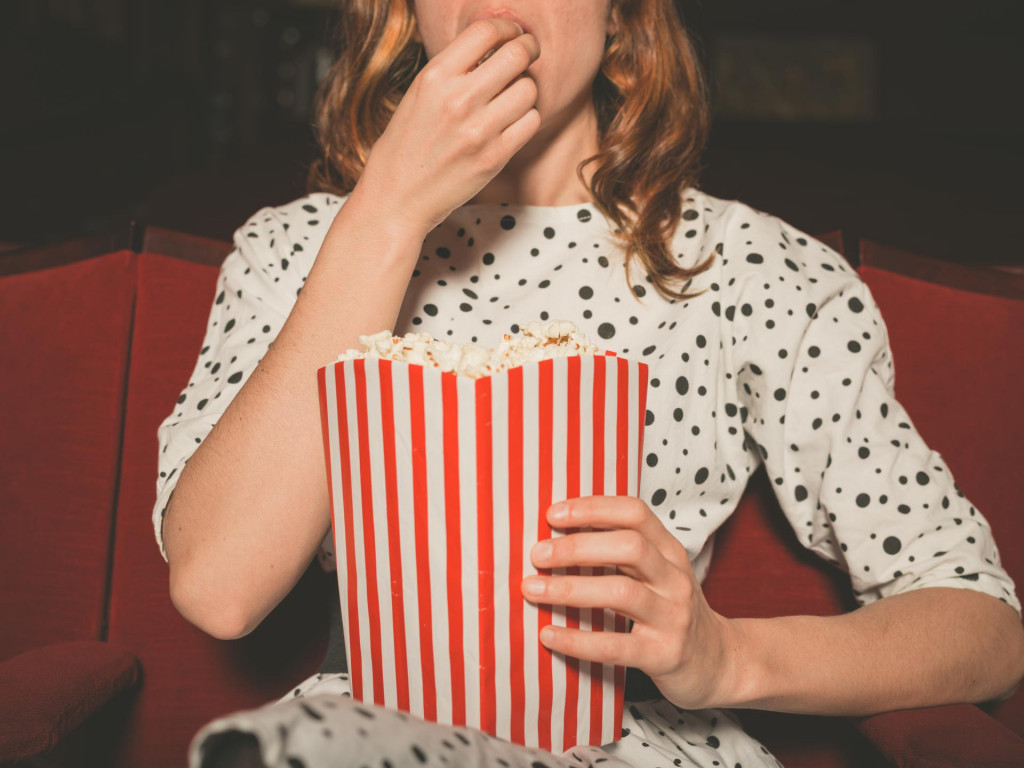 &lt;p&gt;A young woman is watching a movie and is eating popcorn at the cinema&lt;/p&gt;
