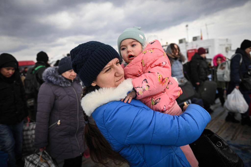 Žena drži bebu dok među ostalim izbjeglicama iz Ukrajine izlazi s trajekta