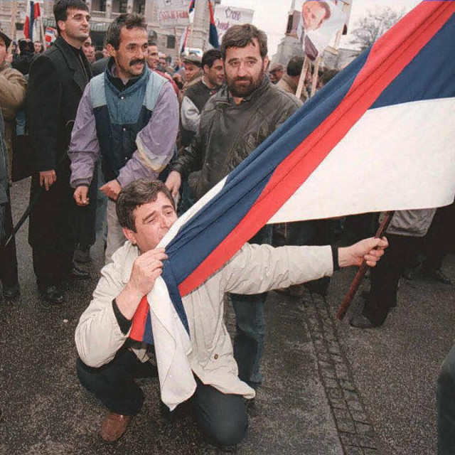 &lt;p&gt;Srpski pobornik Slobodana MIloševića 1990-ih ljubi srpsku zastavu, očito pod dojmom &amp;#39;sankcija kao vanjske prijetnje i napada na vlastiti život&amp;#39;&lt;/p&gt;
