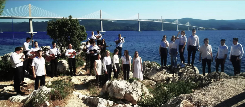 &lt;p&gt;Grupa mladih pjevača i svirača ispred Pelješkog mosta&lt;/p&gt;