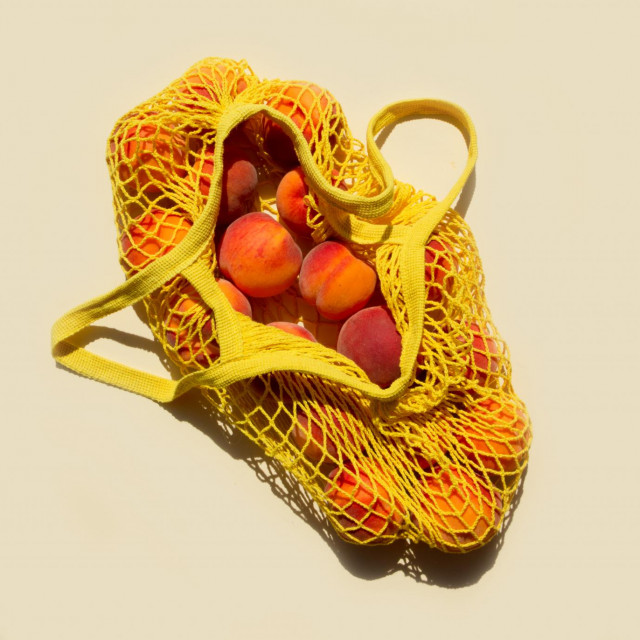 &lt;p&gt;Ripe peaches in a mesh bag or string bag on light yellow background. Flat lay. Zero waste. Top view.&lt;/p&gt;