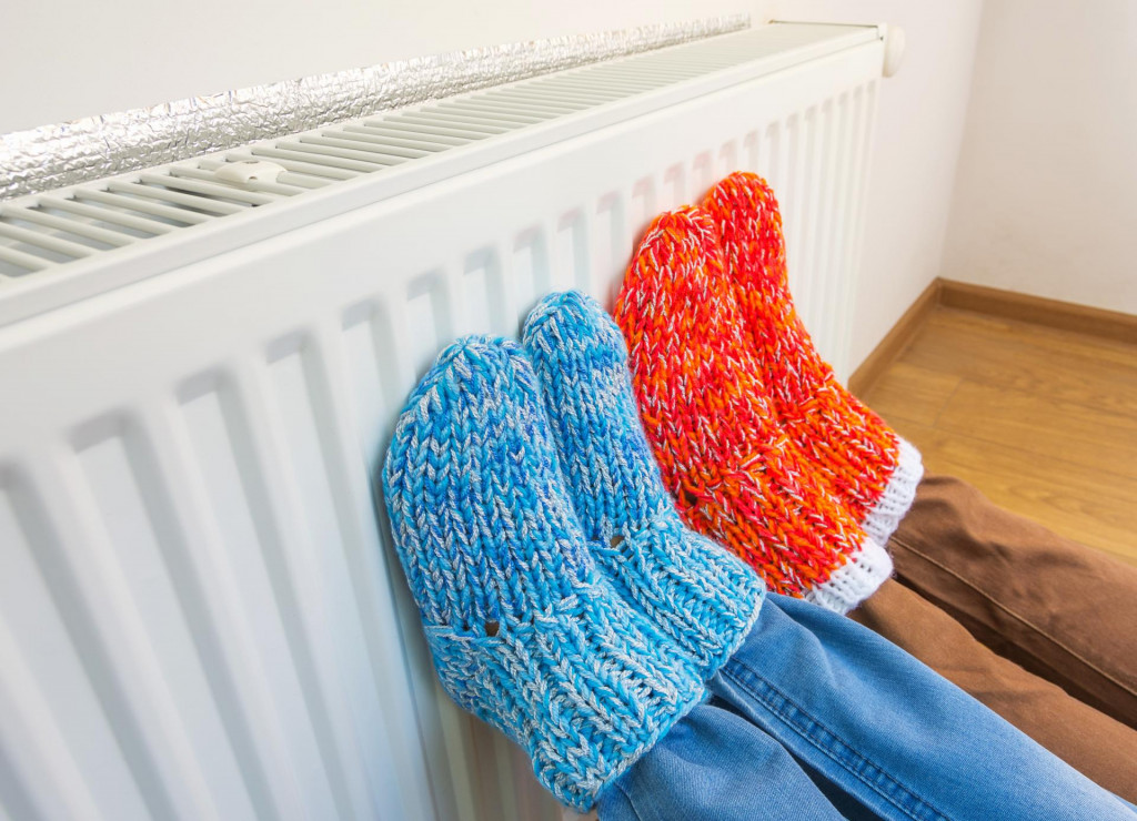 &lt;p&gt;Family wearing colorful pair of knitted wool socks warming cold feet in front of heating radiator in winter time. Electric or gas heater at home. The symbolic image of the heating season at home.&lt;/p&gt;