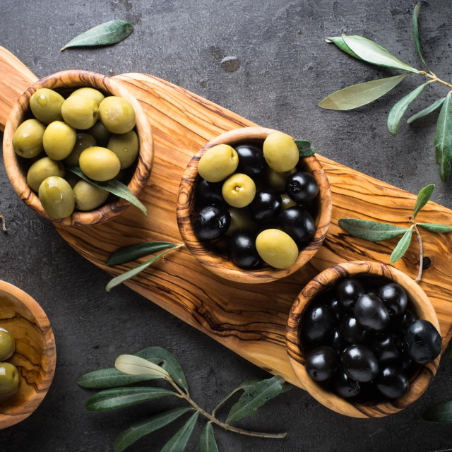 &lt;p&gt;Black and green olives in wooden bowls. Top view on black background.&lt;/p&gt;