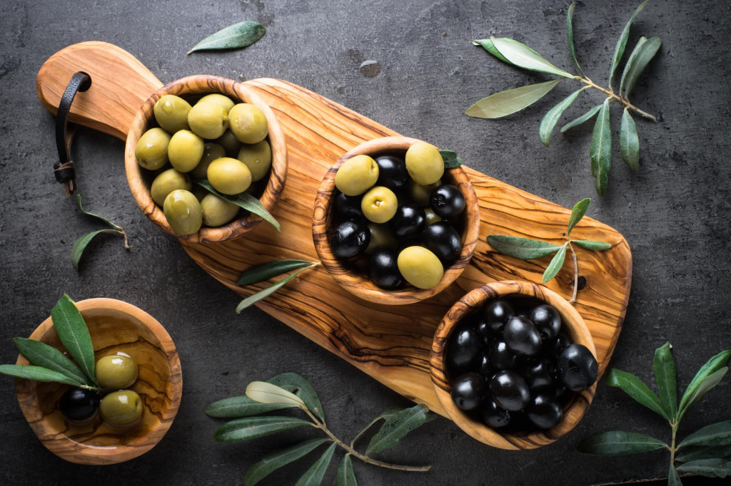 &lt;p&gt;Black and green olives in wooden bowls. Top view on black background.&lt;/p&gt;
