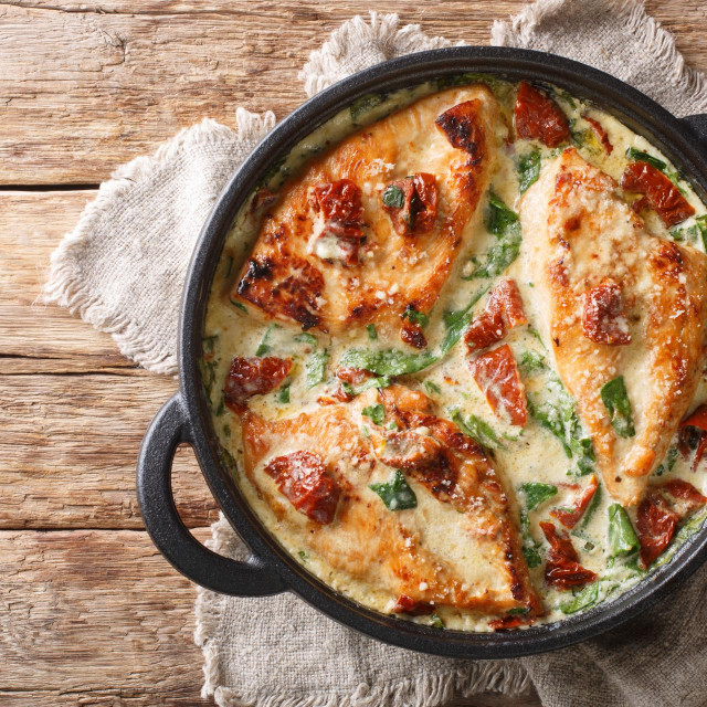 &lt;p&gt;Main course baked chicken with sun-dried tomatoes and spinach in cheese sauce close-up in a pan on the table. Horizontal top view from above&lt;/p&gt;