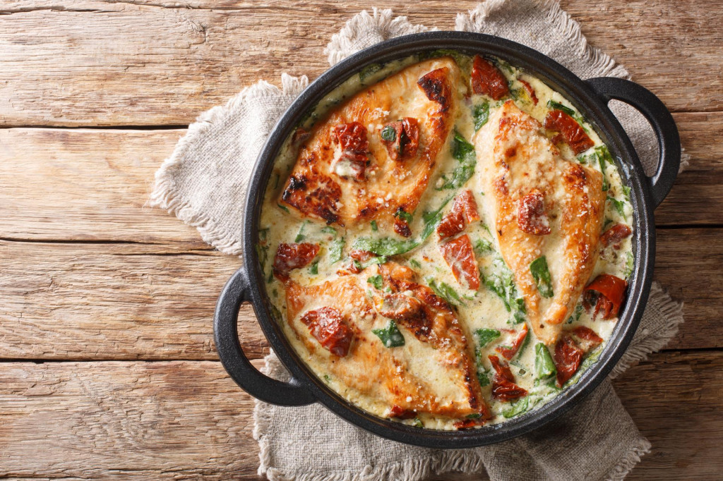 &lt;p&gt;Main course baked chicken with sun-dried tomatoes and spinach in cheese sauce close-up in a pan on the table. Horizontal top view from above&lt;/p&gt;