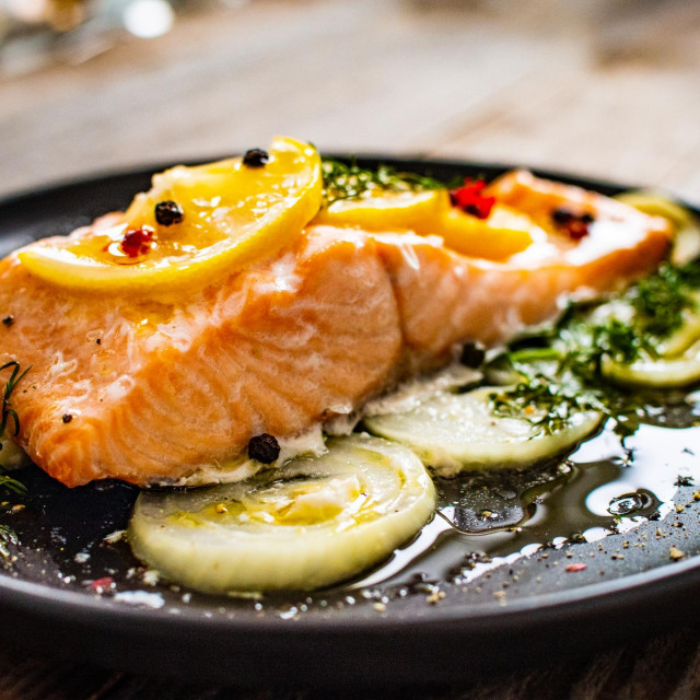 &lt;p&gt;Roasted salmon steak with lemon, and onion served on black plate on wooden table&lt;/p&gt;