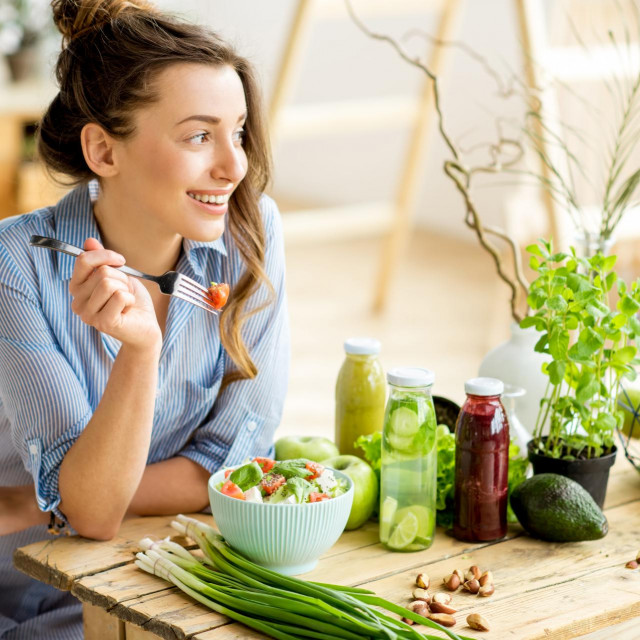 &lt;p&gt;Young and happy woman eating healthy salad sitting on the table with green fresh ingredients indoors&lt;/p&gt;