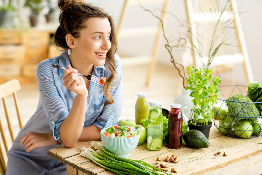 &lt;p&gt;Young and happy woman eating healthy salad sitting on the table with green fresh ingredients indoors&lt;/p&gt;