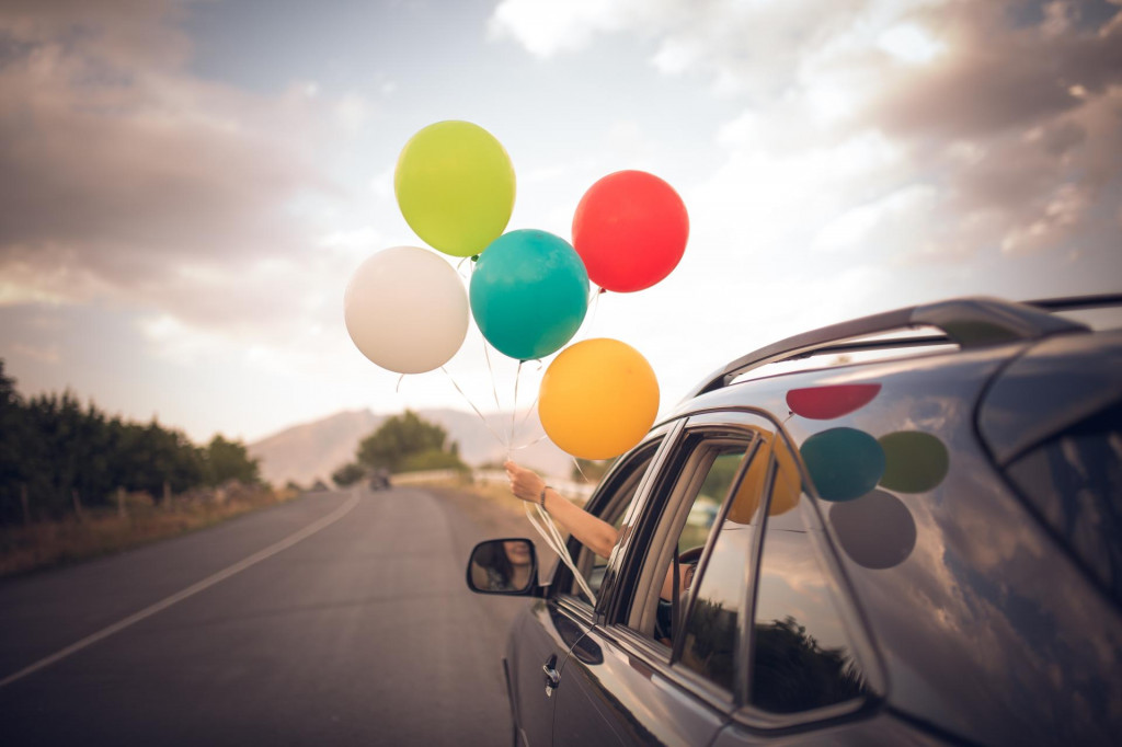 &lt;p&gt;Girl holds colorful balloons out from the window of the car. Freedom, happiness, road trip and celebration concept.&lt;/p&gt;
