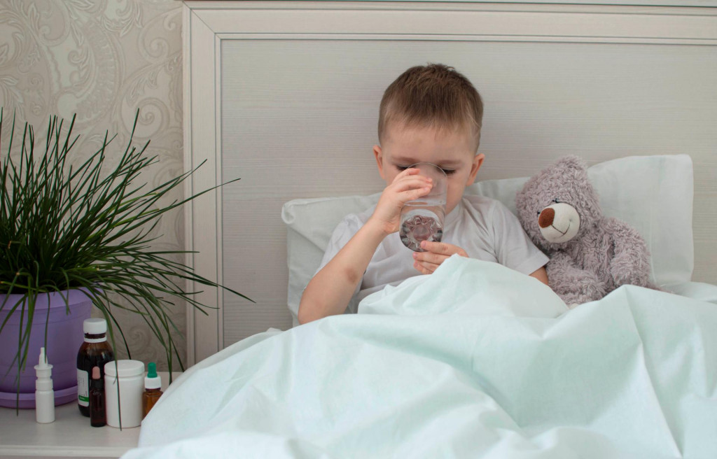 &lt;p&gt;A sick little boy, wrapped in a blanket, lies on the bed and drinks water. He is on sick leave at home.&lt;/p&gt;