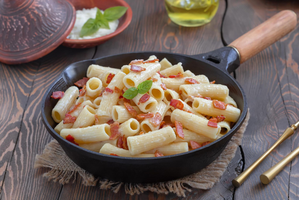 &lt;p&gt;Pasta Alla Gricia. Rigatoni pasta with bacon and pecorino cheese served in frying pan with bowl of grated cheese on background. Dark background, selective focus, horizontal.&lt;/p&gt;