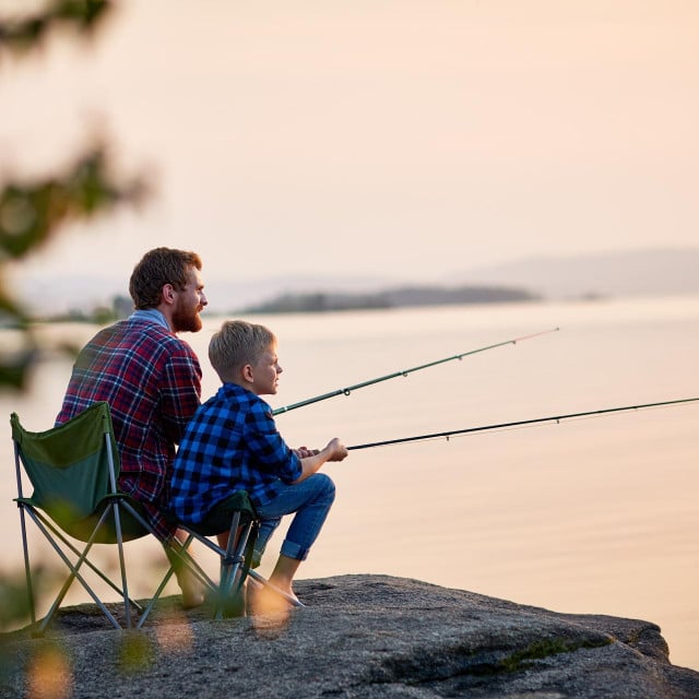 &lt;p&gt;Side view portrait of father and son sitting together on rocks fishing with rods in calm lake waters with landscape of setting sun, both wearing checkered shirts, shot from behind tree&lt;/p&gt;