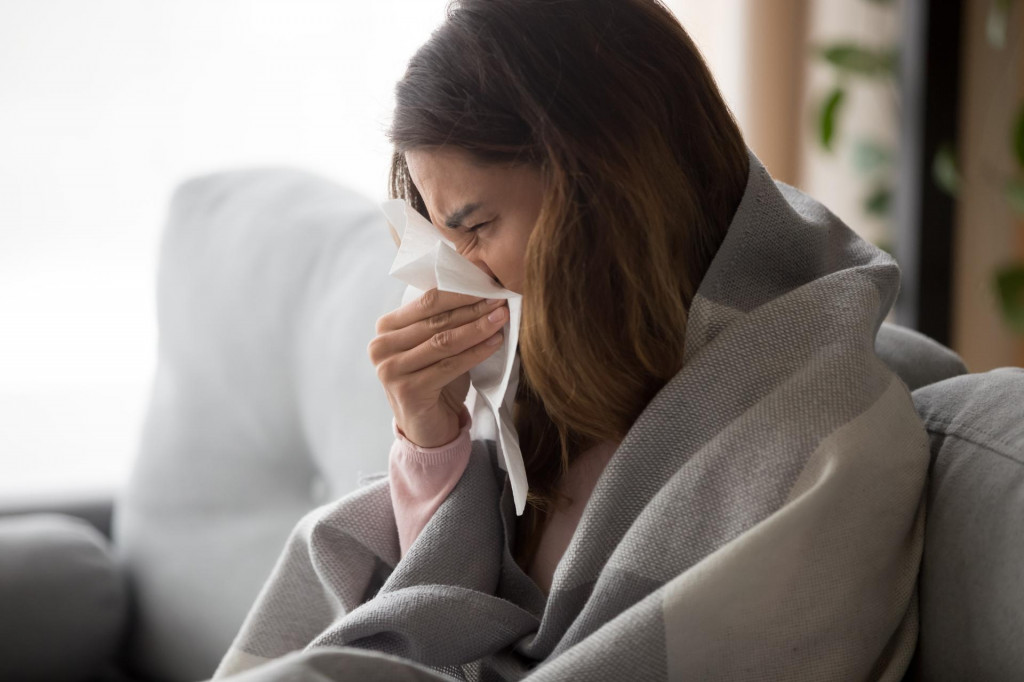 &lt;p&gt;Ill upset young woman sitting on sofa covered with blanket freezing blowing running nose got fever caught cold sneezing in tissue, sick girl having influenza symptoms coughing at home, flu concept&lt;/p&gt;