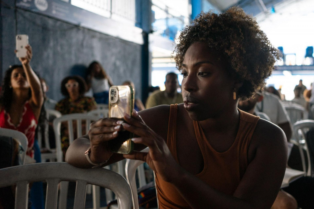 &lt;p&gt;A woman takes pictures during a public hearing on Black Awareness and Reparation for Slavery, at the Portela samba school barrack in Madureira, Rio de Janeiro, Brazil, on November 18, 2023. In 1853, Viscount Jose Bernardino de Sa, a Brazilian nobleman who made his fortune shipping enslaved Africans to the Americas, became the largest investor in the country‘s oldest bank, Banco do Brasil. Now, 170 years later, the bank faces legal action over its historic ties to the slave trade, part of a growing push in Brazil and worldwide for those who profited from slavery to pay reparations. (Photo by Tercio TEIXEIRA/AFP)&lt;/p&gt;