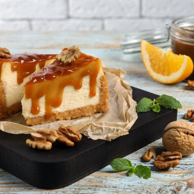 &lt;p&gt;Pieces of delicious caramel cheesecake with walnuts and orange served on wooden table&lt;/p&gt;