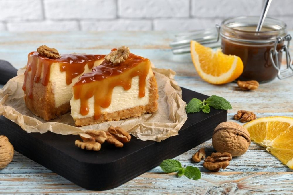 &lt;p&gt;Pieces of delicious caramel cheesecake with walnuts and orange served on wooden table&lt;/p&gt;